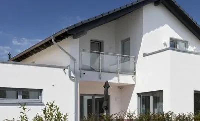 Modernes weißes Einfamilienhaus mit Balkon, Glasgeländer und Fenstern