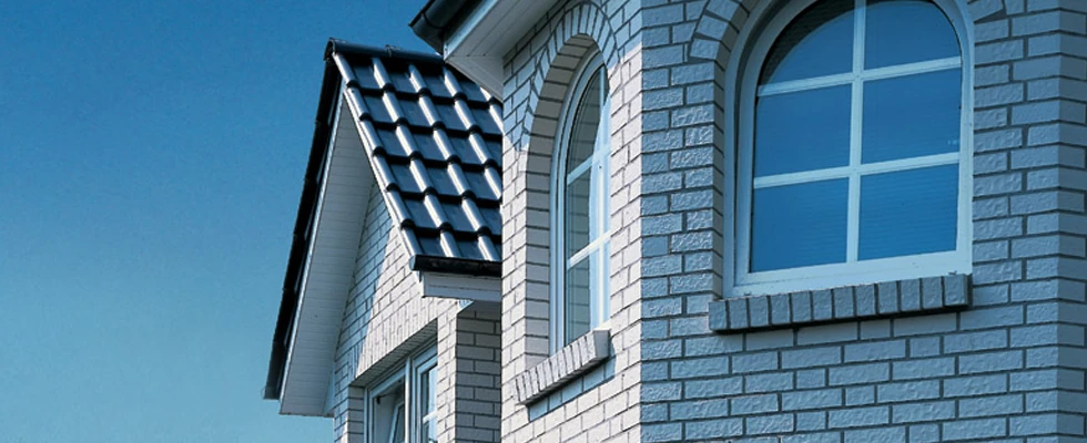 Nahaufnahme einer Hausfassade aus Klinker mit Dachziegeln und Fenstern